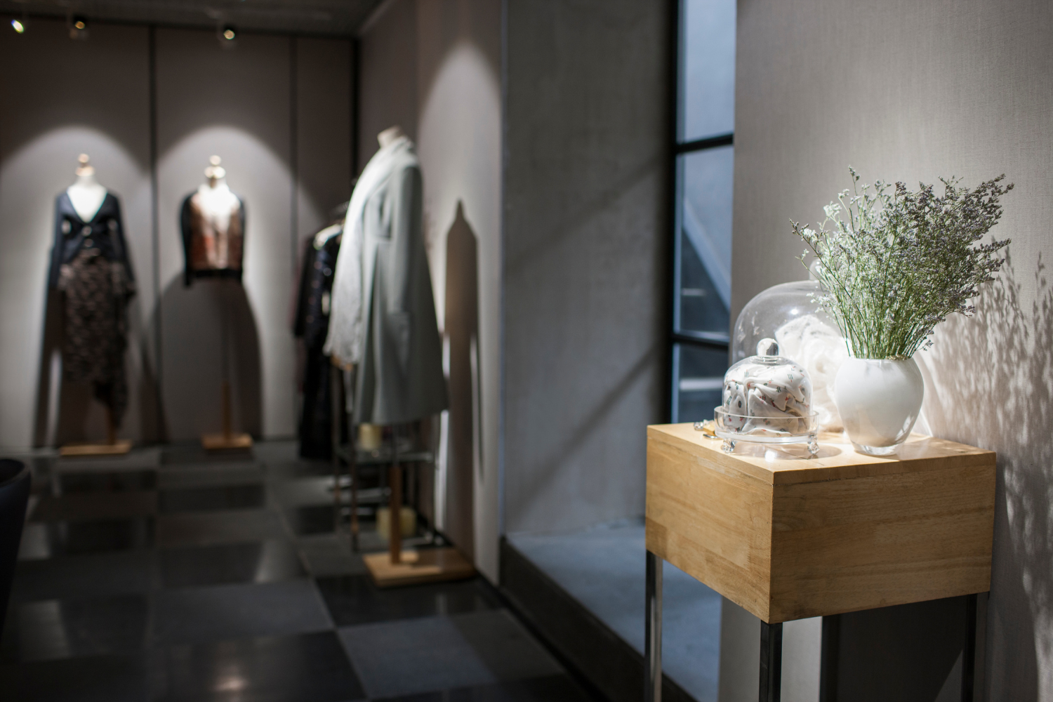 visual merchandiser dressing window display in contemporary fashion or lifestyle retail store, creative product storytelling, premium natural light